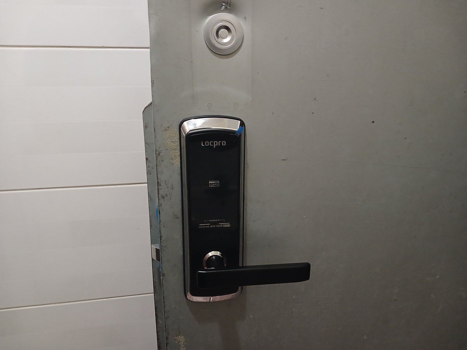 덕양구 관산동 출장 — 회색 철문에 단 검은 레버형 도어락과 문 위쪽의 둥근 은색 부품